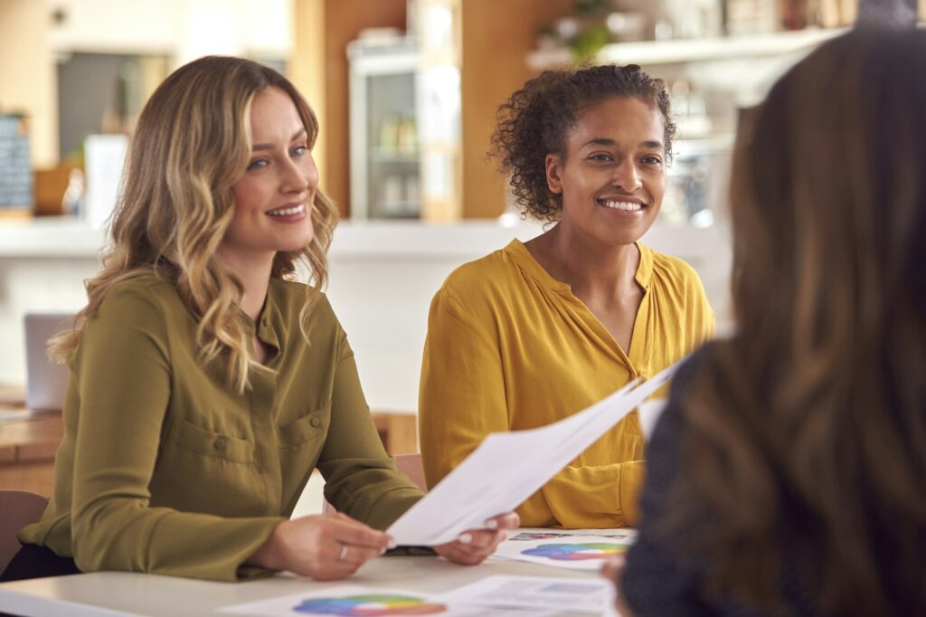 Group Of Female Business Colleagues Having Informal Meeting Around Table In Office Coffee Shop